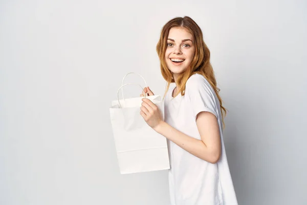 Mujer con un paquete blanco en sus manos hace una compra en una tienda de estilo de vida — Foto de Stock