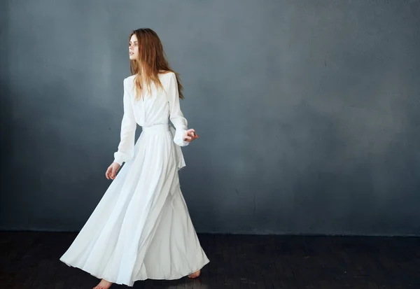Жінка в білій сукні босоніж танцює весело темний фон — стокове фото