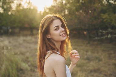 Beyaz elbiseli neşeli kadın doğada poz veriyor. 