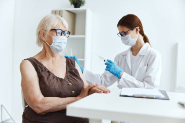Yaşlı bir kadının aşı aşısı şırıngası olan doktor pasaport.