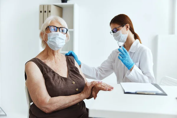 백신을 맞기 위해 병원에서 의료용 마스크를 쓰고 있는 연로 한 여자 — 스톡 사진