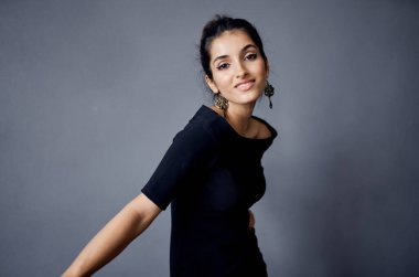 Güzel bir kadın, sandalyenin yanında duran küpeler siyah elbise yaşam tarzı stüdyosu.