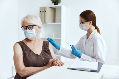 Aşı aşısı pasaportu için hastanede maske takan yaşlı kadın.