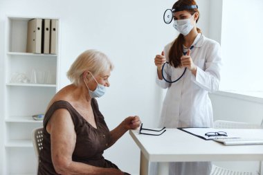 Doktor steteskopundaki yaşlı kadın hasta.