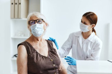 Yaşlı kadın hasta doktor aşı pasaportunun yanında.
