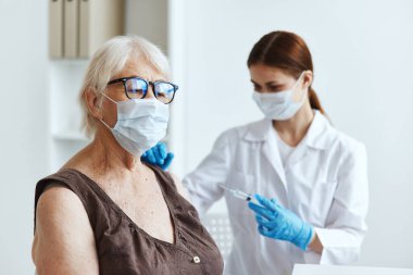 Beyaz önlüklü hemşire kol aşısı pasaportuna iğne yapıyor.