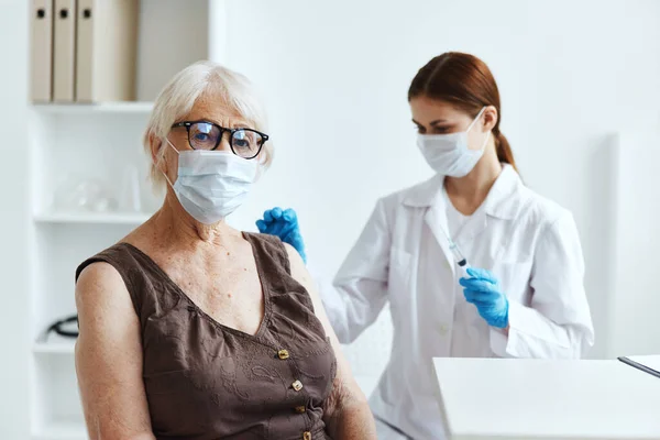 Anziana donna che indossa una maschera medica accanto al medico covid-19 passaporto — Foto Stock