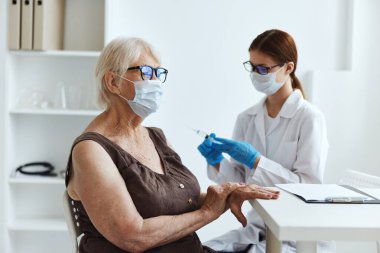 Tıbbi maske hemşiresi kol aşısı pasaportuna enjeksiyon yapıyor.