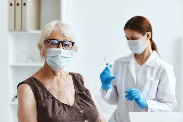 예방 접종을 위해 병원에서 의료용 마스크를 착용하고 있는 나이든 여성 — 스톡 사진