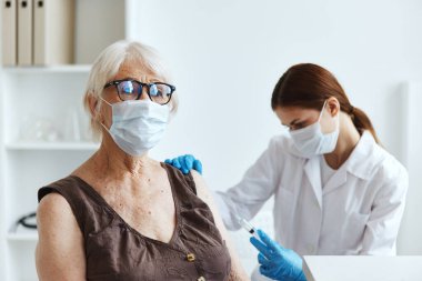 Doktorun yanındaki yaşlı kadın pasaport.