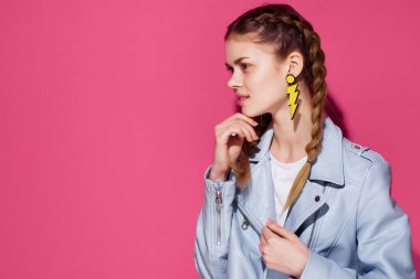 Mavi ceketli çekici bir kadın takı küpeleri takıyor.