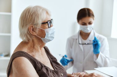 Tıbbi maske takan yaşlı bir kadın. Aşılama, güvenlik ve sağlık hizmetleri.