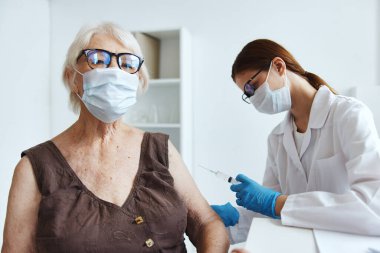 Doktorun pasaportunun yanında tıbbi maske takan yaşlı bir kadın.