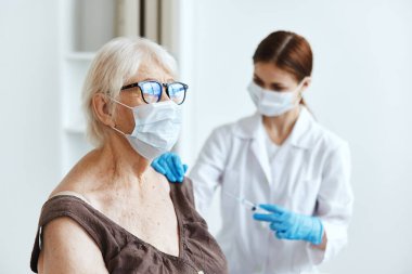 Kadın doktor, kollara dokunulmazlık koruma pasaport iğnesi yapıyor.