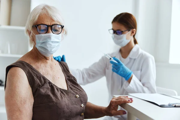흰옷을 입고 있는 간호사 가연로 한 여성의 건강 관리에 대한 백신 접종 — 스톡 사진