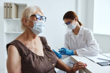 Doktorun pasaportunun yanında tıbbi maske takan yaşlı kadın.