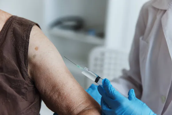 Médico con una jeringa hace una inyección en el brazo protección de la inmunidad pasaporte covid primer plano —  Fotos de Stock