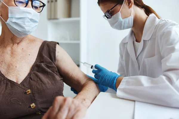 Medicinsk mask sjuksköterska vaccination av en äldre kvinna immunitetsskydd covid pass — Stockfoto