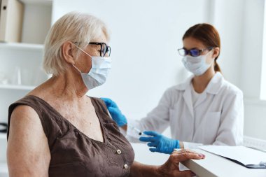 Tıbbi maske hemşiresi kol sağlığı hizmetine enjeksiyon yapıyor.