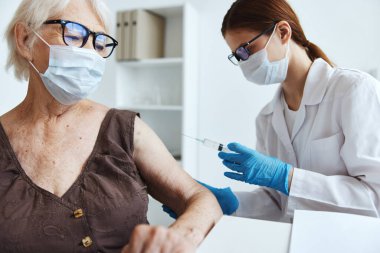 Yaşlı bir kadın sağlık hizmetine şırınga ile aşı olan doktor.