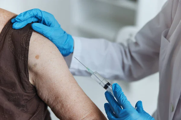 Médecin avec une seringue fait une injection dans le passeport de vaccin bras gros plan — Photo