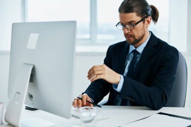 Ofis çalışanı bir bilgisayar belgesinin önünde çalışıyor.