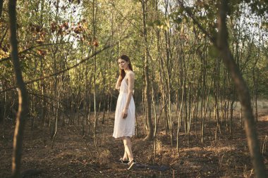 Kadın ormanda ağaçların arasında yaz elbisesi.