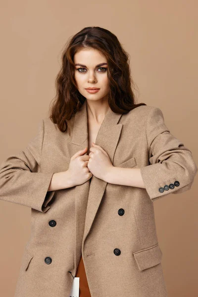 Güzel, çekici bir kadın. Ceket, bej bir arka plan.