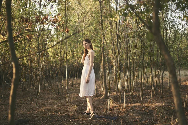 Kadın ormanda ağaçların arasında yaz elbisesi.