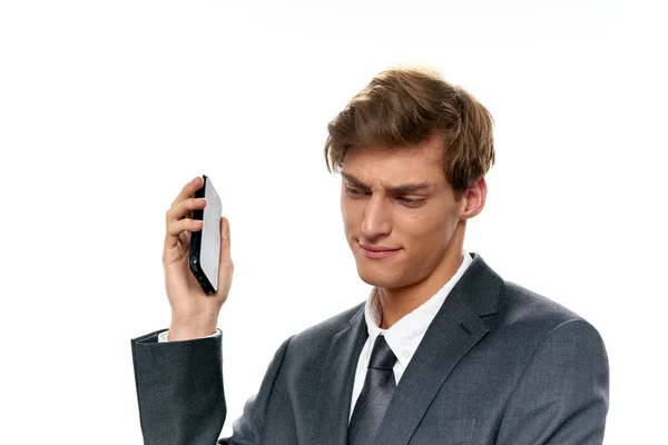 Zakenman met een mobiele telefoon in zijn hand op een lichte achtergrond klassiek pak shirt — Stockfoto