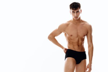 Beyaz arka planda çıplak bir bedende şortlu seksi bir sporcu. 