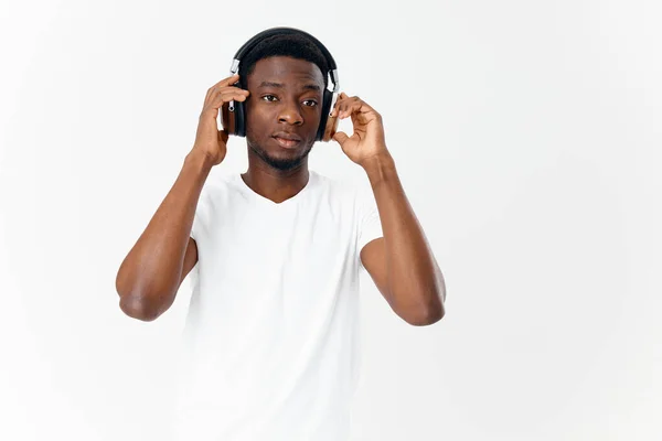 Hombre de apariencia africana en camiseta blanca escucha música con auriculares en tecnología — Foto de Stock