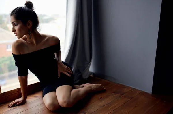 Morena em um vestido preto perto da janela posando modelo de moda — Fotografia de Stock