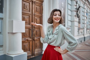 Şehirde kırmızı etekli güzel bir kadın yürüyor.