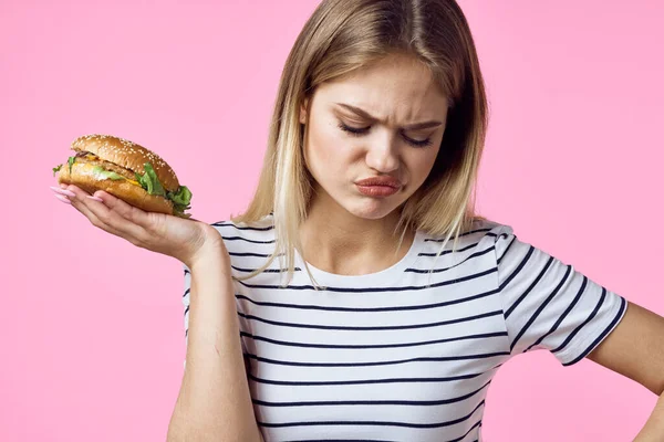 Vrolijk vrouw met fast food in haar handen snacks heerlijk roze achtergrond — Stockfoto