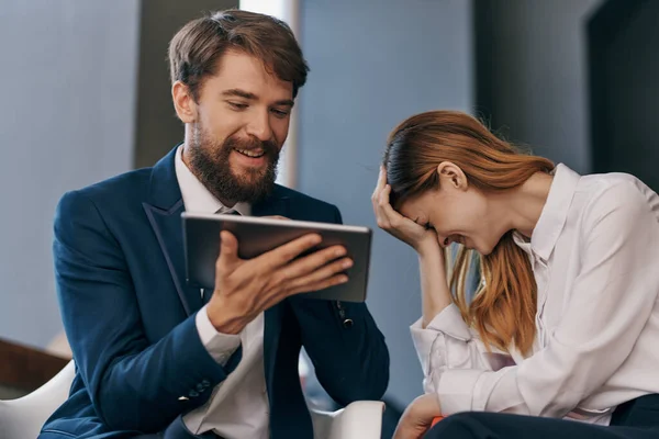 man and woman in business suits looking at the tablet technology office