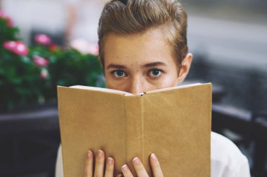 Elinde kitap olan bir öğrenci temiz hava eğitiminde yürüyor.