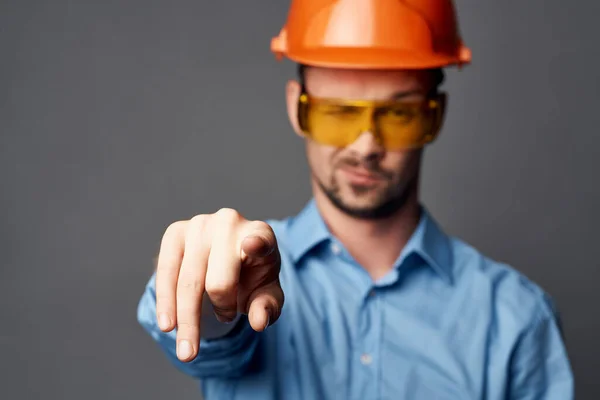 Людина в помаранчевому жорсткому капелюсі жовті окуляри будівельні роботи безпеки — стокове фото