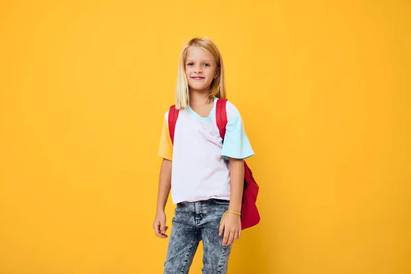 Bonito menina loira escola mochila amarelo fundo — Fotografia de Stock