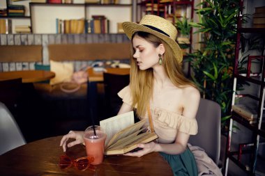 Kafe modasında kitap okuyan neşeli bir kadın.