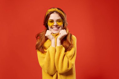 Sarı süveter gözlüklü güzel bir kadın. Moda duyguları kırmızı arka plan.