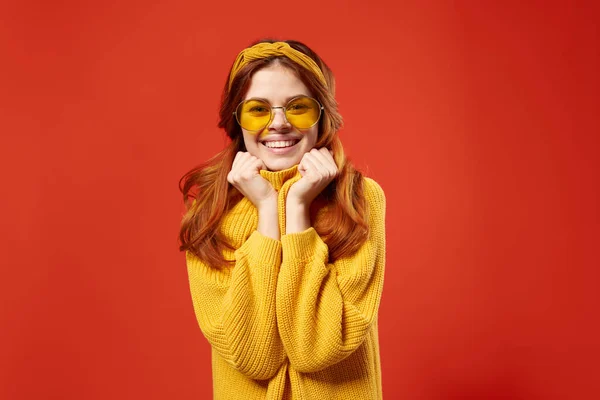 Vacker kvinna i gul tröja glasögon mode känslor röd bakgrund — Stockfoto
