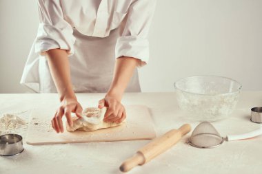 Şef, mutfak masasında hamur yoğuruyor, profesyonel yemek pişiriyor.