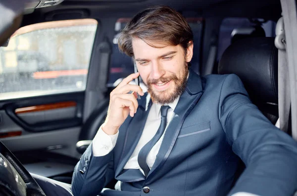 Homens de negócios em um terno em um carro uma viagem à comunicação de trabalho por telefone — Fotografia de Stock