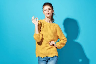 Sarı kazaklı kadın Stüdyo mavi arka planda poz veriyor