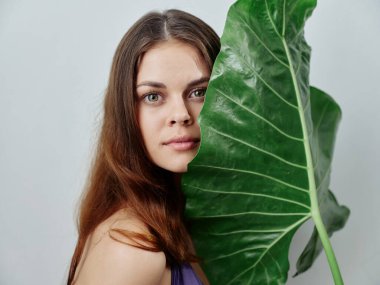 Güzel kızıl saçlı, yeşil palmiye yapraklı, mayo giymiş bir kadın.