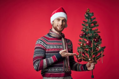 Noel Baba şapkalı neşeli adam Noel süsleri Noel stüdyosunda poz veriyor.