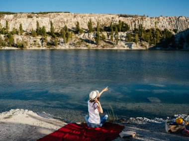 Nehir kenarında beyaz şapkalı bir kadın.