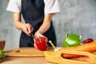 Ev hanımı mutfakta sebze doğruyor.