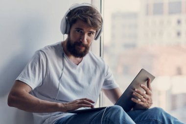 Neşeli adam pencere eşiğinde oturup rahatlıyor.